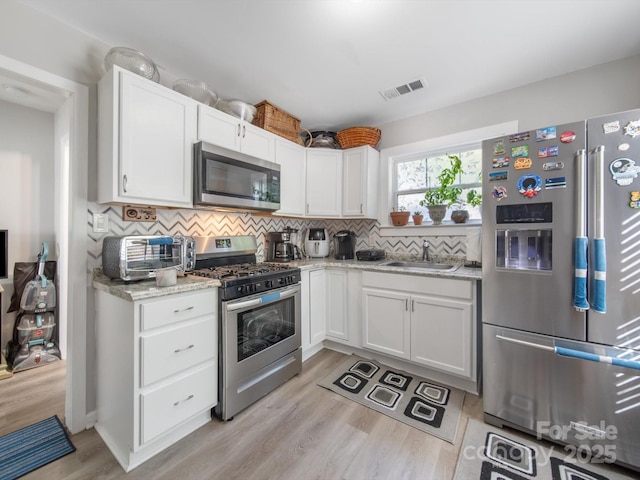 339 Arnold St, Rock Hill, SC 29730 - kitchen featuring stainless steel appliances, a sink, light wood finished floors, backsplash, and white cabinetry