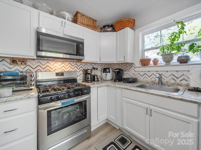 339 Arnold St, Rock Hill, SC 29730 - kitchen with appliances with stainless steel finishes, a sink, decorative backsplash, and white cabinets