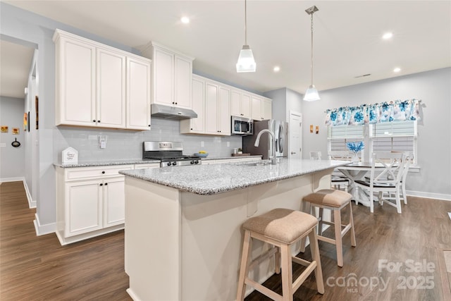 5079 Skyfest Dr, Charlotte, NC 28215 - kitchen featuring appliances with stainless steel finishes, under cabinet range hood, baseboards, decorative backsplash, and dark wood-type flooring