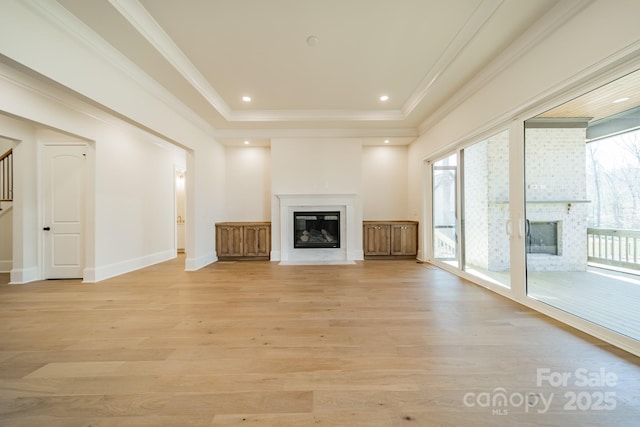 608 Deodar Cedar Dr Unit 69, Matthews, NC 28104 - unfurnished living room featuring a fireplace with flush hearth, plenty of natural light, light wood finished floors, a raised ceiling, and crown molding