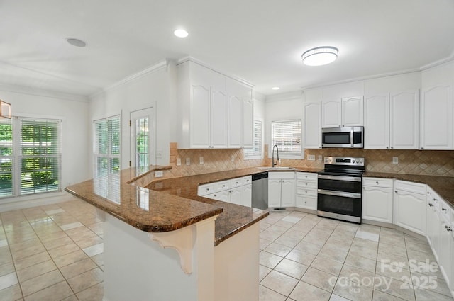 201 Limerick Dr, Matthews, NC 28104 - kitchen with stainless steel appliances, a peninsula, light tile patterned floors, a sink, and ornamental molding