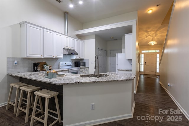 4637 Willow Glen Rd, Harrisburg, NC 28075 - kitchen with under cabinet range hood, white appliances, a sink, a peninsula, and backsplash