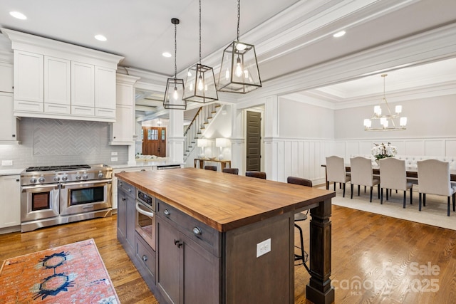 2221 Kenmore Ave, Charlotte, NC 28204 - kitchen with stainless steel appliances, wooden counters, ornamental molding, a breakfast bar area, and white cabinets