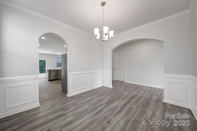 300 Kennerly Center Dr, Mooresville, NC 28115 - spare room with arched walkways, wainscoting, wood finished floors, a chandelier, and a decorative wall