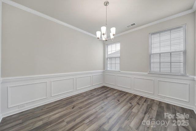 300 Kennerly Center Dr, Mooresville, NC 28115 - unfurnished dining area featuring a chandelier, crown molding, dark wood-style flooring, wainscoting, and a decorative wall
