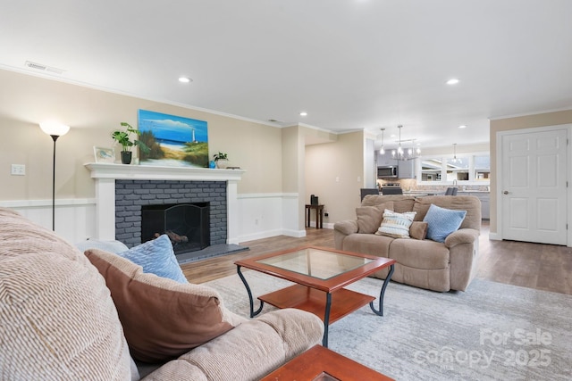 1035 15th Ave NW, Hickory, NC 28601 - living room with ornamental molding, wood finished floors, a brick fireplace, a chandelier, and recessed lighting