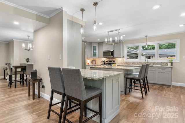 1035 15th Ave NW, Hickory, NC 28601 - kitchen with appliances with stainless steel finishes, a chandelier, a breakfast bar, gray cabinetry, and crown molding