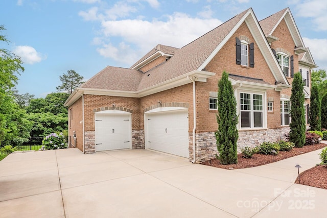 3009 Ocaso Ct, Matthews, NC 28104 - view of home's exterior with driveway, a shingled roof, stone siding, an attached garage, and brick siding