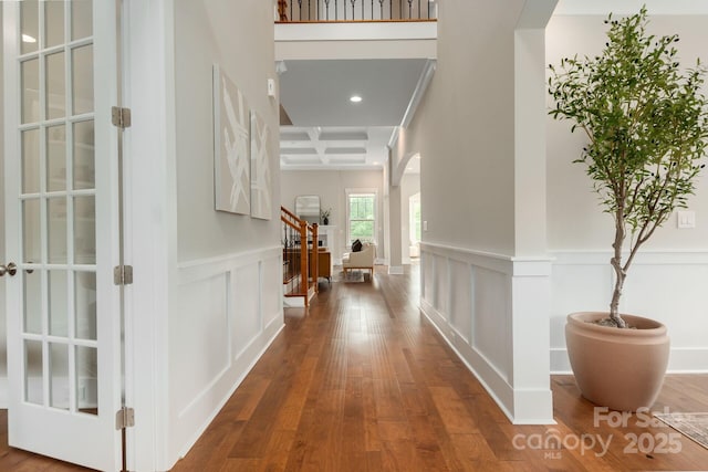 3009 Ocaso Ct, Matthews, NC 28104 - hallway featuring arched walkways, coffered ceiling, wood finished floors, beam ceiling, and a wainscoted wall