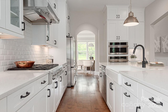3009 Ocaso Ct, Matthews, NC 28104 - kitchen with extractor fan, stainless steel appliances, white cabinets, dark wood finished floors, and arched walkways