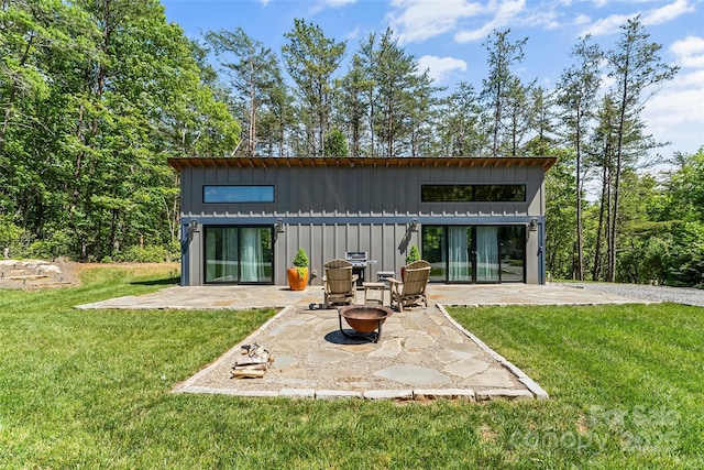 2508 Wolf Pit Rd, Morganton, NC 28655 - rear view of property featuring board and batten siding, a patio area, a lawn, and an outdoor fire pit