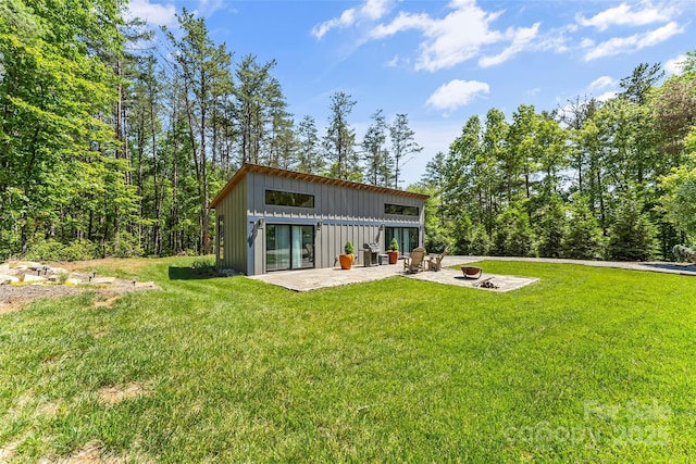 2508 Wolf Pit Rd, Morganton, NC 28655 - back of property featuring board and batten siding, a patio, a lawn, and an outdoor fire pit