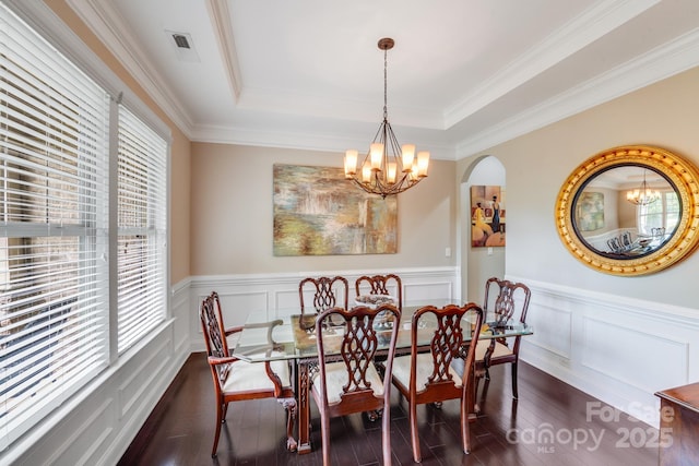 8070 Clems Branch Rd, Indian Land, SC 29707 - dining space featuring dark wood-style floors, a chandelier, a tray ceiling, arched walkways, and a wainscoted wall