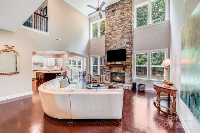 8070 Clems Branch Rd, Indian Land, SC 29707 - living room with high vaulted ceiling, a ceiling fan, dark wood-style flooring, a stone fireplace, and arched walkways
