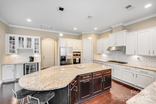 8070 Clems Branch Rd, Indian Land, SC 29707 - kitchen with appliances with stainless steel finishes, under cabinet range hood, beverage cooler, white cabinetry, and recessed lighting