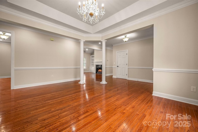 182 Kensington Dr, Forest City, NC 28043 - unfurnished living room featuring hardwood / wood-style flooring, a warm lit fireplace, baseboards, ornate columns, and ornamental molding