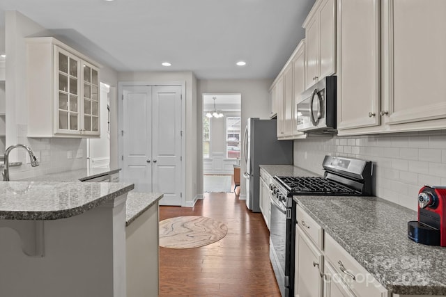 308 Planters Way, Mount Holly, NC 28120 - kitchen with stainless steel appliances, a sink, decorative backsplash, dark wood-style floors, and glass insert cabinets