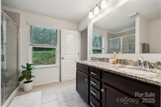 5113 Saddleback Dr, Mount Holly, NC 28120 - bathroom with double vanity, a shower stall, tile patterned floors, and baseboards