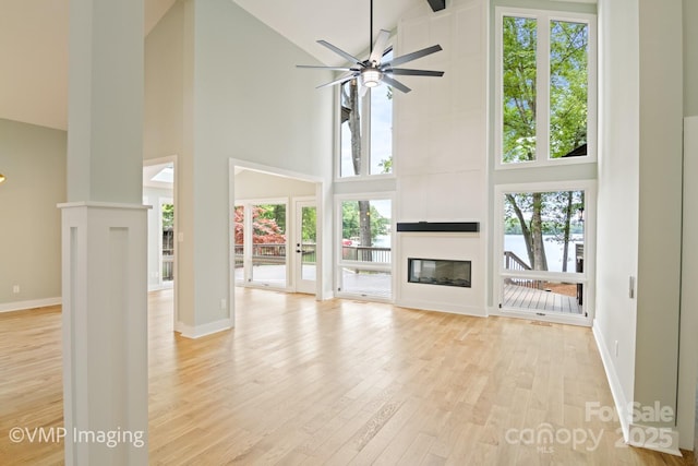 449 Windward Dr, Davidson, NC 28036 - unfurnished living room with high vaulted ceiling, a large fireplace, healthy amount of natural light, a water view, and light wood-type flooring
