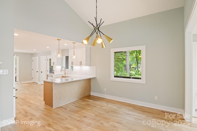 449 Windward Dr, Davidson, NC 28036 - kitchen with a chandelier, a peninsula, white cabinets, decorative backsplash, and recessed lighting