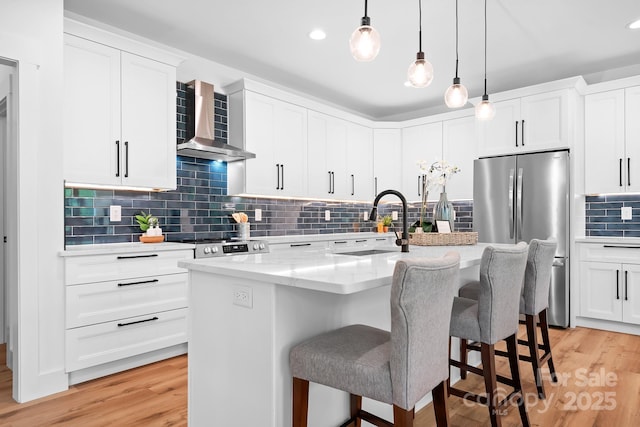 106 Arbor Dr, Waxhaw, NC 28173 - kitchen with stainless steel appliances, wall chimney range hood, a center island with sink, light wood-type flooring, and recessed lighting