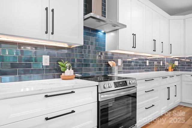 106 Arbor Dr, Waxhaw, NC 28173 - kitchen featuring stainless steel electric stove, wall chimney range hood, white cabinets, and light stone counters