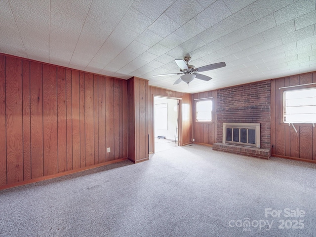 201 Robinson Rd, Gastonia, NC 28056 - unfurnished living room featuring baseboards, a brick fireplace, wooden walls, a ceiling fan, and carpet flooring