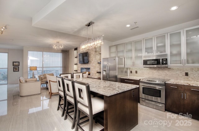 333 W Trade St Unit 1304, Charlotte, NC 28202 - kitchen with stainless steel appliances, decorative backsplash, dark brown cabinets, a breakfast bar, and a chandelier