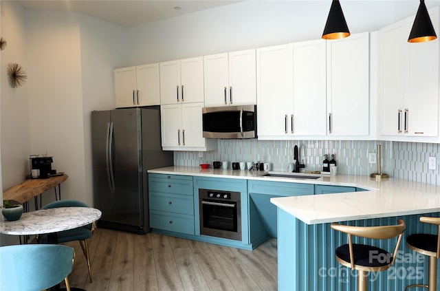 333 W Trade St Unit 1304, Charlotte, NC 28202 - kitchen featuring stainless steel appliances, a sink, decorative backsplash, light wood finished floors, and a kitchen bar