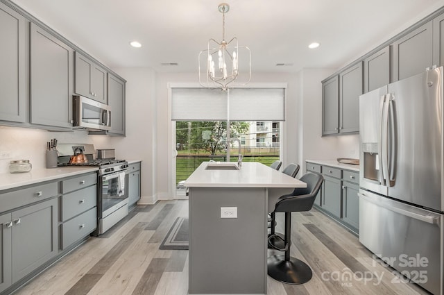 235 S Bruns Ave, Charlotte, NC 28208 - kitchen featuring stainless steel appliances, a sink, gray cabinets, a chandelier, and light wood-type flooring
