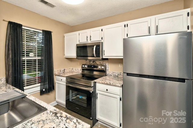 6401 Windsor Gate Ln, Charlotte, NC 28215 - kitchen with stainless steel appliances, white cabinets, plenty of natural light, a textured ceiling, and baseboards