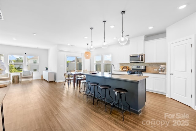 3938 Isenhour Rd, Kannapolis, NC 28081 - kitchen featuring stainless steel appliances, recessed lighting, a kitchen breakfast bar, backsplash, and light wood-style floors