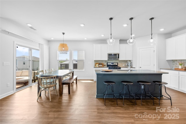 3938 Isenhour Rd, Kannapolis, NC 28081 - kitchen with stainless steel appliances, tasteful backsplash, wood finished floors, recessed lighting, and white cabinets