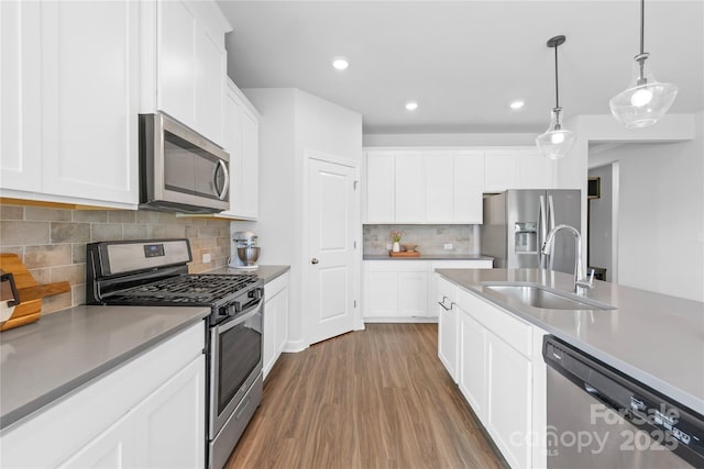 3938 Isenhour Rd, Kannapolis, NC 28081 - kitchen featuring appliances with stainless steel finishes, a sink, wood finished floors, decorative backsplash, and pendant lighting