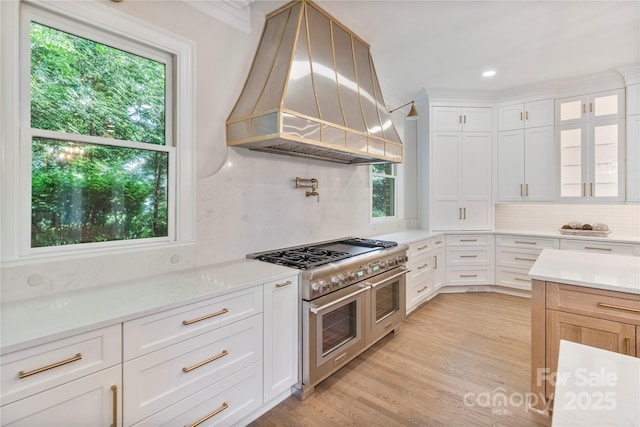 8721 Lake Challis Ln, Charlotte, NC 28226 - kitchen with double oven range, custom exhaust hood, backsplash, light wood-type flooring, and white cabinetry