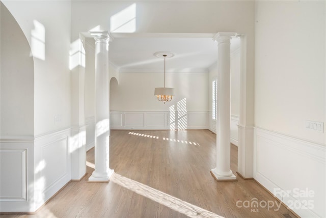 8721 Lake Challis Ln, Charlotte, NC 28226 - hallway featuring ornamental molding, wood finished floors, a wainscoted wall, a decorative wall, and decorative columns