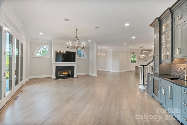 8721 Lake Challis Ln, Charlotte, NC 28226 - living room featuring a chandelier, recessed lighting, ornamental molding, light wood-style flooring, and a lit fireplace