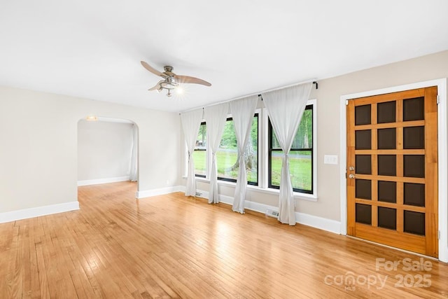 7022 Lakeside Dr, Charlotte, NC 28215 - unfurnished room featuring ceiling fan, baseboards, light wood finished floors, and arched walkways