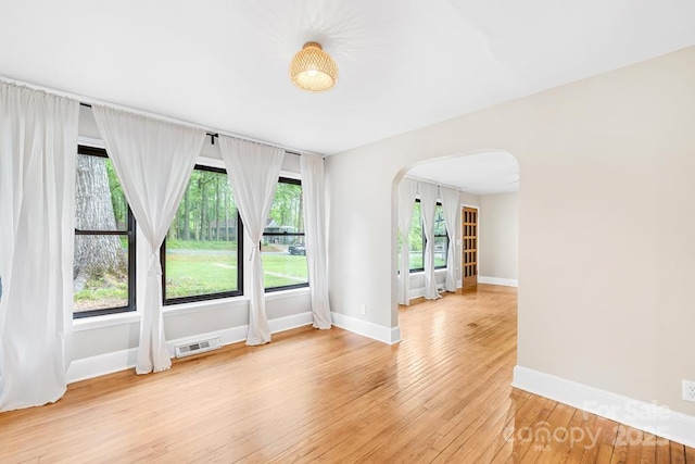 7022 Lakeside Dr, Charlotte, NC 28215 - unfurnished room with arched walkways, healthy amount of natural light, light wood-type flooring, and baseboards