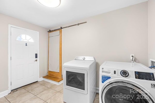 7022 Lakeside Dr, Charlotte, NC 28215 - laundry area featuring independent washer and dryer, a barn door, baseboards, and light tile patterned flooring