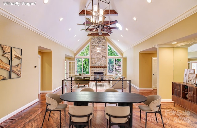 305 E High Point Ln, Hendersonville, NC 28791 - dining space featuring a chandelier, wood finished floors, baseboards, a large fireplace, and ornamental molding