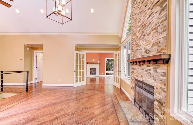 305 E High Point Ln, Hendersonville, NC 28791 - unfurnished living room featuring a stone fireplace, wood finished floors, crown molding, baseboards, and a high ceiling