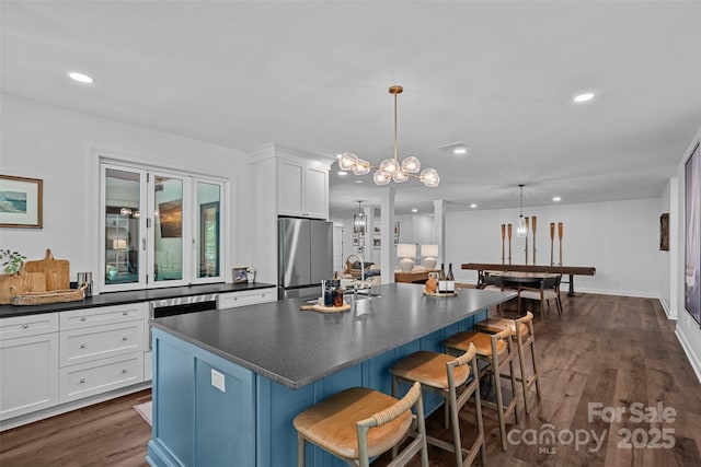 117 Walking Horse Trl, Davidson, NC 28036 - kitchen with freestanding refrigerator, dark countertops, dark wood-type flooring, white cabinets, and a breakfast bar