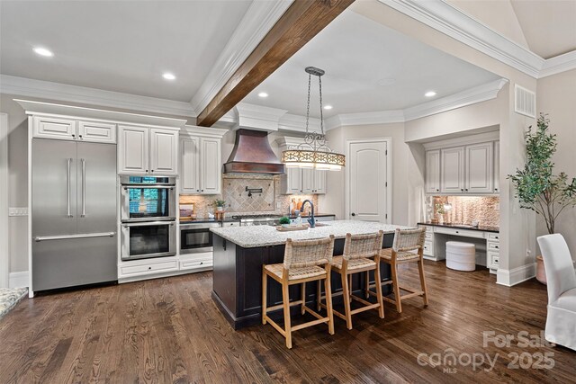 117 Walking Horse Trl, Davidson, NC 28036 - kitchen with wall chimney exhaust hood, built in appliances, tasteful backsplash, crown molding, and a kitchen island with sink