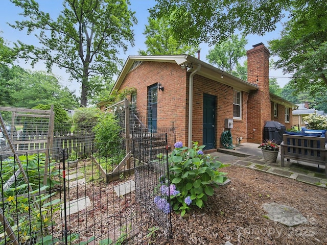 2026 Knell Dr, Charlotte, NC 28212 - back of house featuring brick siding, a vegetable garden, a patio area, and a chimney