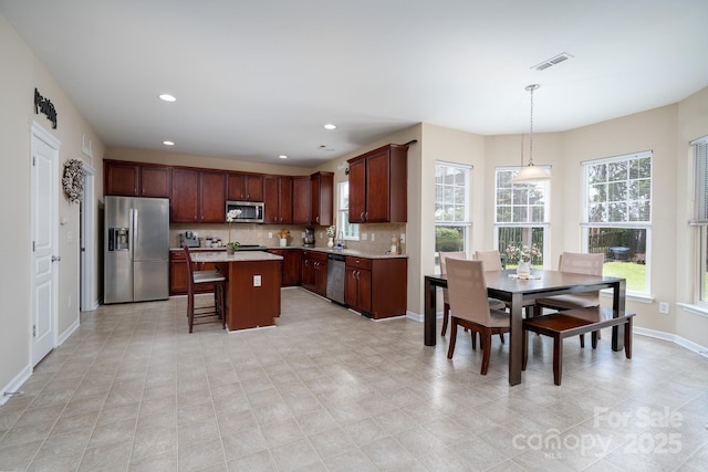 4915 Juniper Grove Ct SW, Concord, NC 28027 - kitchen with stainless steel appliances, light countertops, a breakfast bar area, backsplash, and a center island