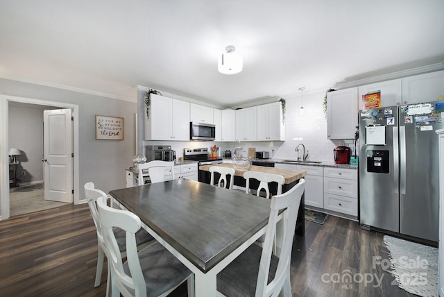2302 Douglas Rd, Lancaster, SC 29720 - kitchen with stainless steel appliances, tasteful backsplash, dark wood finished floors, white cabinetry, and crown molding