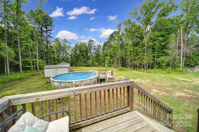 2302 Douglas Rd, Lancaster, SC 29720 - wooden terrace featuring a storage unit, an outdoor pool, a lawn, and a view of trees