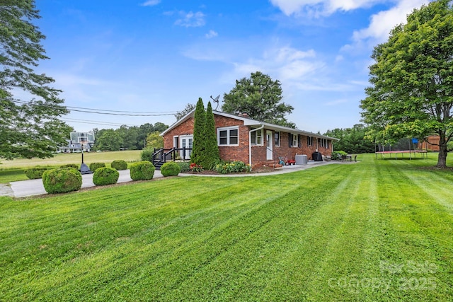 242 Pattys Chapel Rd, Fletcher, NC 28732 - view of home's exterior featuring brick siding, a trampoline, and a yard