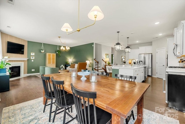 15515 Laverack Ln, Davidson, NC 28036 - dining space with wood finished floors, stairs, a glass covered fireplace, recessed lighting, and a chandelier